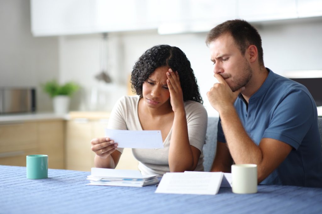 Worried couple reviewing paperwork at home, symbolizing policyholders questioning denied claims and asking 'Can I sue my insurance company?'