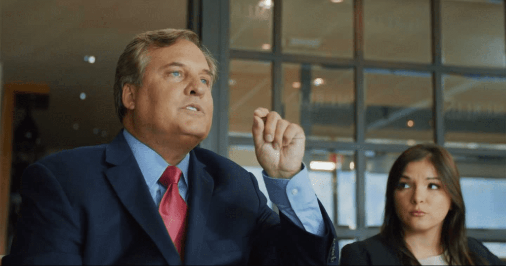 Two attorneys in a professional setting, with one man in a suit speaking confidently and a woman listening attentively — representing legal consultation for property damage claims.
