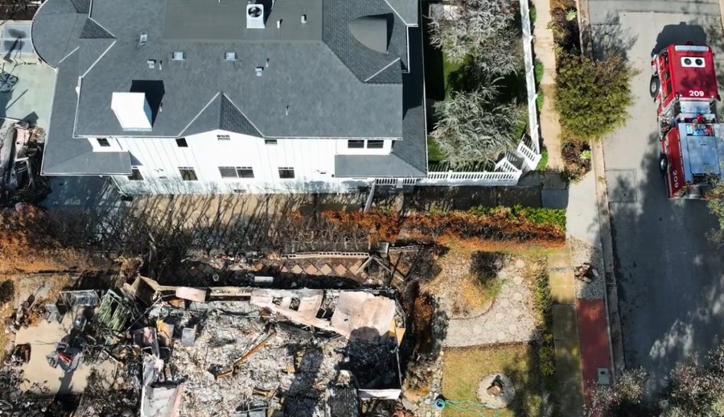 Aerial view showing a home spared next to a neighboring property destroyed by wildfire, illustrating the importance of filing a wildfire insurance claim for property damage and loss even when your home doesn't burn down.