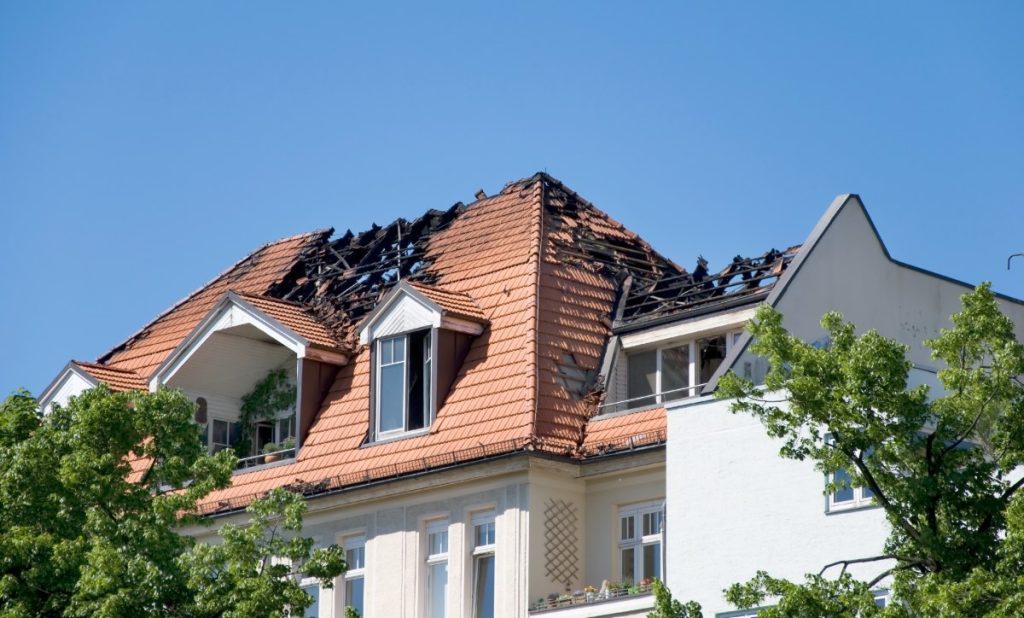 Burned roof of a residential building after a fire, illustrating the type of property damage where a house fire lawyer can help homeowners recover insurance claims and compensation.