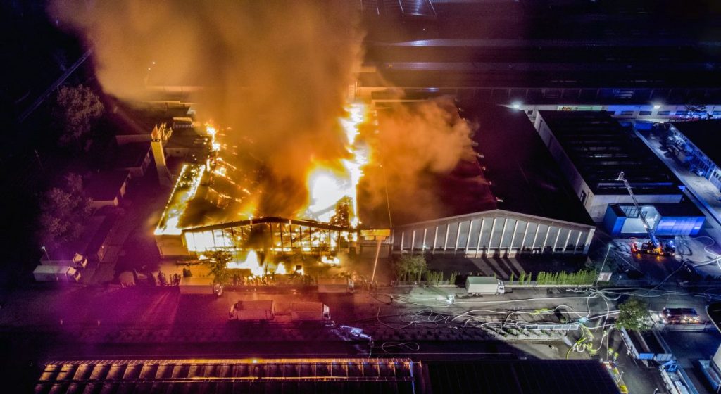 A large commercial building engulfed in flames at night with heavy smoke rising, illustrating the devastation that leads to a commercial fire damage claim.